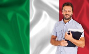 תרגום לאיטלקית בתמונה: סטודנט צעיר מחייך על רקע דגל איטליה אדום לבן ירוק