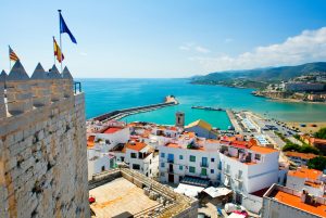 תרגום לספרדית בתמונה נוף לעבר חוף הים בספרד כחול על המצודה דגלים